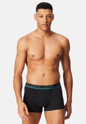 Schwarze Boxershorts mit türkisfarbenem Bund, auf dem die Marke "uncover" zu sehen ist. Der Stoff ist glatt, die Passform eng anliegend und ohne Muster.