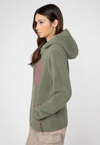 Fleece-Hoodie in Olivgrün mit einer braunen Taschenklappe. Verfügt über eine Reißverschlusstasche und strukturierten Stoff für zusätzliche Wärme.