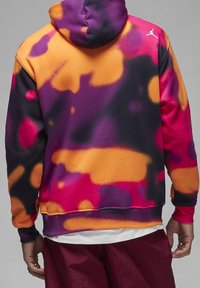 Felpa con cappuccio caratterizzata da un motivo vivace a spruzzo di vernice nei colori viola, arancione e rosa. Realizzata in tessuto morbido con polsini e orlo a coste.