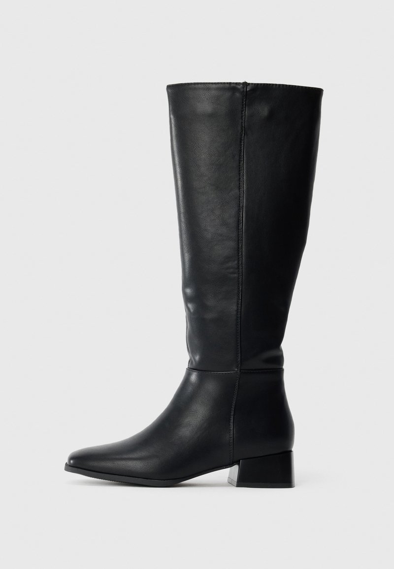 Bottes en cuir noir montantes jusqu'aux genoux, avec un bout pointu et un petit talon bloc. Texture lisse avec un design simple et sans ornements visibles.