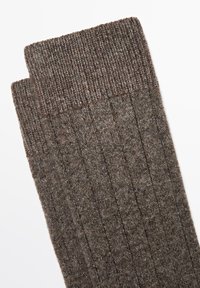 Hnědé žebrované ponožky z texturované tkaniny, s pleteným lemem a vertikálními pruhy, které zajišťují odolný a pohodlný design.