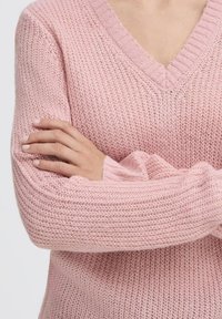 Maglione rosa a maglia con scollatura a V, caratterizzato da un motivo testurizzato e polsini a costine. Il materiale appare morbido e leggero.