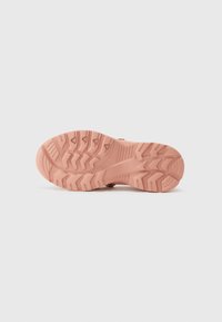 Sole in gomma rosa con scanalature profonde e modelli di trazione. Presenta una superficie texturizzata per una migliore aderenza. Tacco arrotondato con un design robusto.