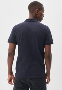 Námorníckomodrá polokošeľa vyrobená z bavlny, s krátkymi rukávmi, klasickým golierom a štítkom na leme. Jednoduchý, čistý dizajn bez viditeľných vzorov.