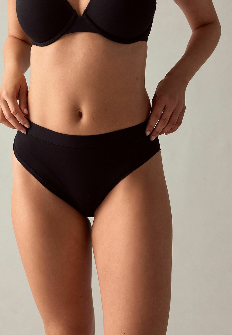 Mutande nere a vita alta con una ampia cintura elastica, texture liscia e design minimalista. Nessun motivo visibile o dettagli metallici.