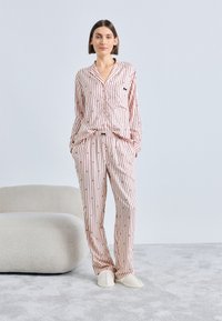 Set de pijamale cu dungi roz, format dintr-o cămașă cu nasturi și pantaloni cu talie elastică. Material neted, cu buzunar la piept și papuci moi.