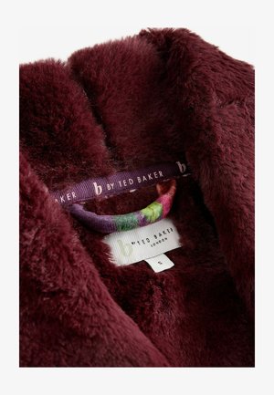 Bordeaux-farbenes Kunstpelzgewebe mit einer weichen Textur. Enthält einen mehrfarbigen Kleiderbügel und ein Pflegeetikett mit der Marke "b by Ted Baker".