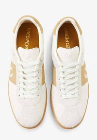 Zapatillas blancas con acentos beige, de ante y tejido texturizado, puntera redonda, cordones planos y un logo en el lateral y en la lengüeta.