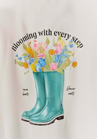 Tyrkysové gumové boty s lesklým povrchem, zdobené květinovým vzorem růžových, žlutých a modrých květin, s textem "Kveteme s každým krokem."