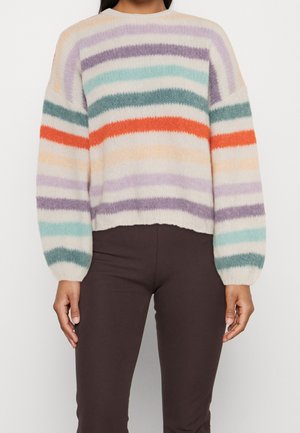 Flauschiger Pullover mit horizontalen Streifen in Lila, Türkis, Orange und Beige, getragen zu dunkelbraunen Hosen, zeigt Oberkörper und Arme.