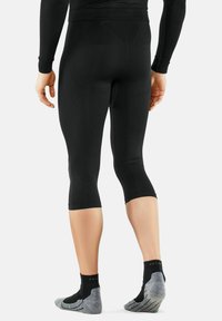Black compression capri leggings with a smooth, fitted design, featuring a mid-calf length and a seamless waistband. Paired with gray textured socks.