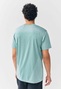 Világoskék, rövid ujjú ing, texturált geometriai mintával, kerek nyakkivágással és laza szabással.