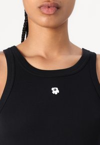 Top negru din bumbac, cu un decolteu rotund, având un mic broderie cu floare albă în centrul său. Textură moale, design ajustat.