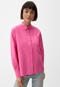 Heldere roze overhem shirt met kraag, lange mouwen en een voorzak. Gemaakt van lichte stof; gladde textuur.