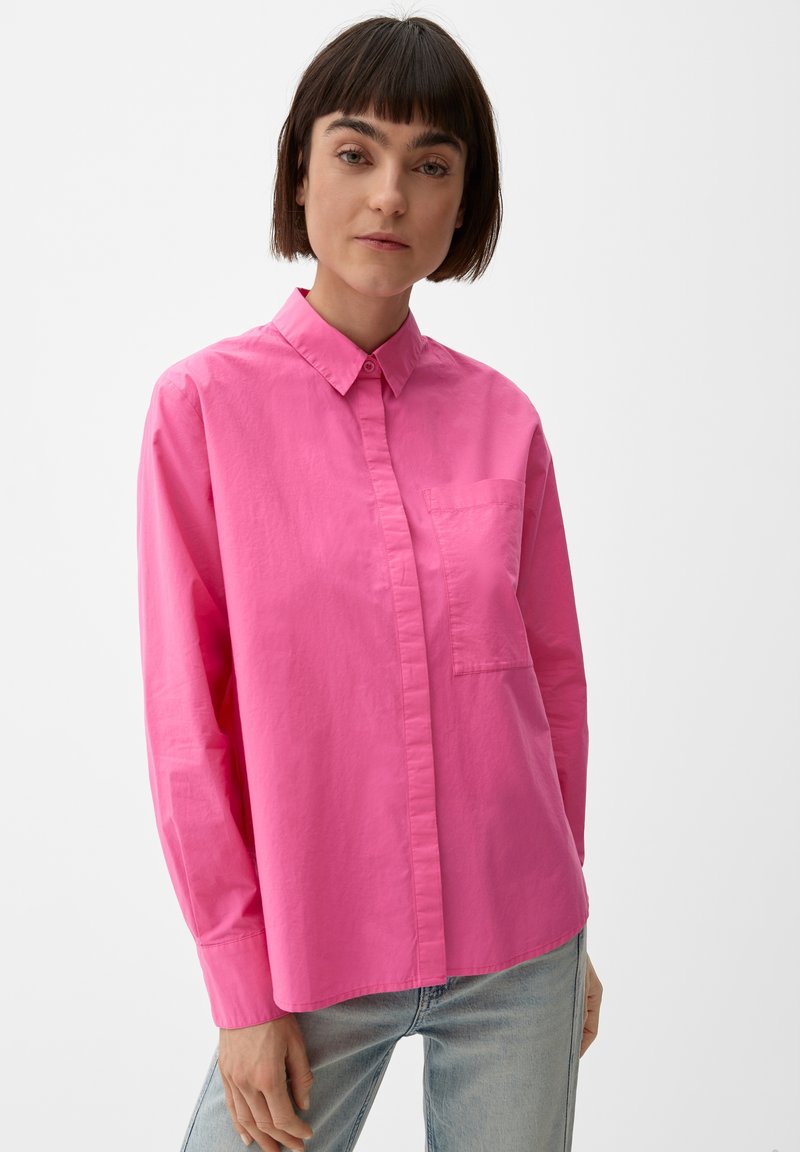Heldere roze overhem shirt met kraag, lange mouwen en een voorzak. Gemaakt van lichte stof; gladde textuur.