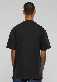 Black cotton t-shirt with a relaxed fit, short sleeves, and a round neckline. Features a small tag at the hem.