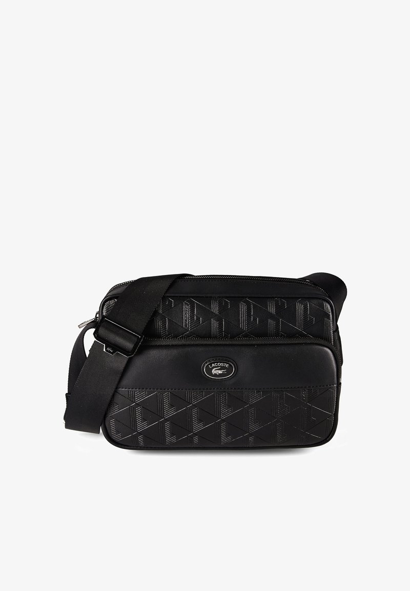 Μαύρη τσάντα Lacoste χιαστί με ανάγλυφο γεωμετρικό σχέδιο, ρυθμιζόμενο λουράκι και μπροστινή τσέπη με φερμουάρ που φέρει το λογότυπο του κροκοδείλου Lacoste.