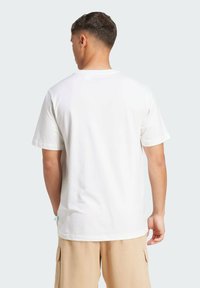 Hvid bomulds T-shirt med korte ærmer, almindelig pasform og rund halsudskæring. Lys beige cargo shorts. Enkel design, ingen synlige mønstre eller logoer.