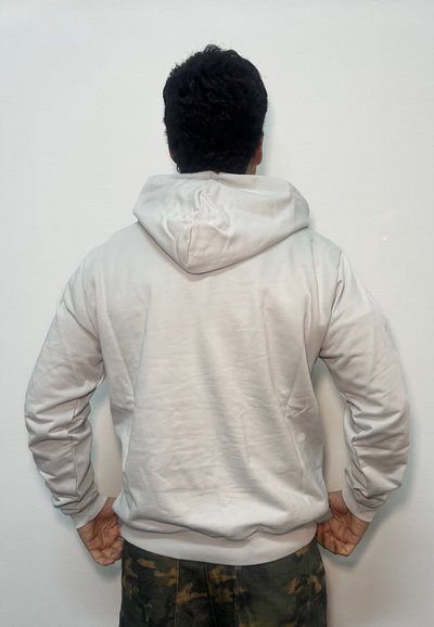 Felpa con cappuccio grigio chiaro con cappuccio ampio, tessuto morbido, polsini e orlo a coste. Vista posteriore mostra un design semplice, senza loghi o motivi visibili.