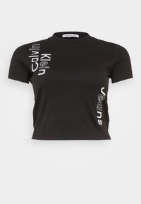Černé zkrácené tričko vyrobené z bavlny, s bílým vertikálním nápisem "Calvin Klein Jeans" na přední straně. Krátké rukávy a kulatý výstřih.