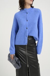 Light blue knitted cardigan with a high collar and black buttons, paired with a black leather skirt featuring a front zipper. Textured fabric.