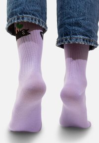 Lawendowe skarpetki z prążkowanym wzorem mają ilustrację kota z zielonymi akcentami. Skarpetki są lekkie i mają gładką teksturę.