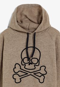 Sudadera beige hecha de una tela suave con un diseño de calavera y huesos cruzados en la parte frontal, que cuenta con una capucha ajustable y mangas raglán.