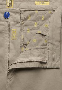 Beige chino's met een gevoerde binnenvoering, voorzien van gele M5-branding, een blauwe knop en een verborgen ritszak.