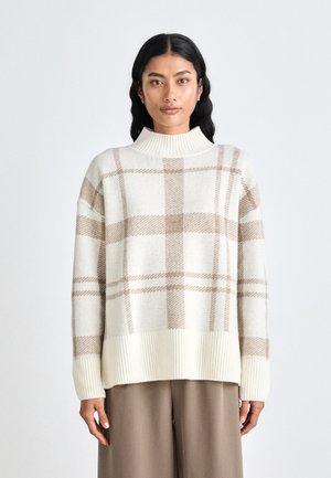 Strickpullover in Creme mit beigem Karomuster, ausgestattet mit einem hohen, gerippten Kragen und geripptem Saum. Das Design ist oversized mit herunterhängenden Schultern.