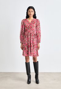 Pink floral dress with long sheer sleeves, a wrap design, and a flared hem, paired with knee-high black leather boots.