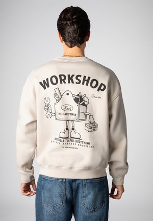 Hellbeiges Sweatshirt mit einem Grafikdruck eines Handwerkers mit Werkzeugen. Rippbündchen an Ärmeln und Saum. Legeres, entspannter Schnitt.