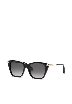 Lunettes de soleil carrées noires avec verres dégradés gris foncé et fines branches dorées, montrées sous un léger angle sur fond blanc.