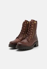 Botines de cuero marrón con cordones en la parte delantera y cremalleras laterales, que presentan una superficie texturizada, puntera redonda y suela de goma negra gruesa.