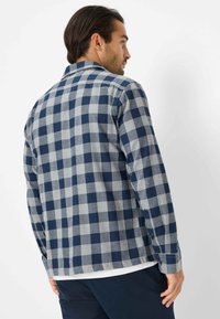 Marineblauw en grijs geblokt flanellen shirt met kraagontwerp, lange mouwen en knoopmanchetten. Zachte textuur en relaxte pasvorm.