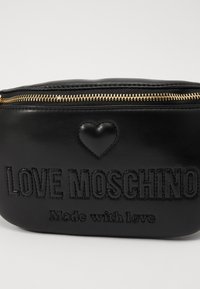 Pochette in pelle nera con zip dorata, caratterizzata da testo embossato "LOVE MOSCHINO" e un piccolo dettaglio a forma di cuore, texture liscia e forma compatta.