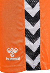 Oranga sportshorts med svart och vit chevronmönster, med meshstruktur och en logotyp på nedre vänstra sidan.