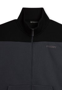 Chaqueta con cremallera en gris oscuro y un panel superior negro. Hecha de tela suave, cuenta con un cuello alto y el logo "FREDDY" en gris.