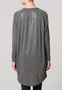 Šedá tunika s dlouhým rukávem z měkké látky, s lesklým texturovaným zadním dílem, zaobleným lemem a raglánovými rukávy.