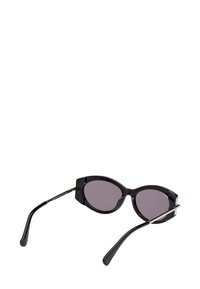 Černé sluneční brýle s ovalním rámem, tmavými skly a tenkými nožičkami, umístěné s otevřenými stranami na bílém pozadí.
