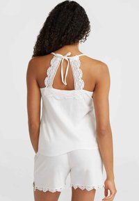 Hvid ærmeløs top med en scalloped blondekant og en bundet ryglukning, parret med matchende shorts med en blondekant.