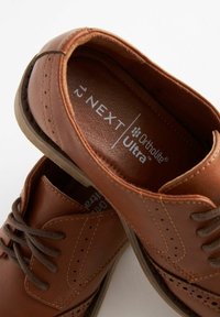 Chaussures en cuir marron avec des détails perforés, design à lacets et semelles ortholites® Ultra. Semelle marron robuste complétant l'empeigne.