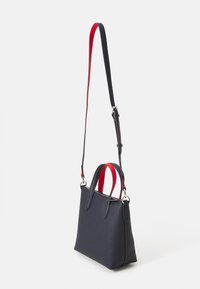 Borsa a tracolla di pelle testurizzata blu navy con doppi manici rossi e una tracolla regolabile. Presenta una forma strutturata e hardware in argento.