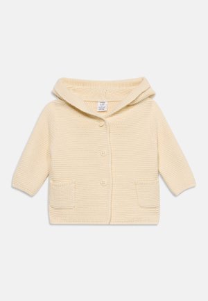 Babystrickjacke in Cremefarben mit Kapuze, drei vorderen Knöpfen und zwei kleinen Fronttaschen.