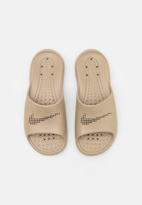 Beige szandálok nyitott orral, perforált Nike logóval és kör alakú tapadó mintázattal rendelkező, textúrált talpbetéttel.