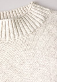 Pull en laine crème avec un col haut en côtes et une texture douce. Possède un corps lisse avec une couture régulière et un design classique.
