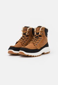 Brown leather and black fabric ankle boots with white midsole, fur lining, and orange laces. Features textured materials and treaded soles.
