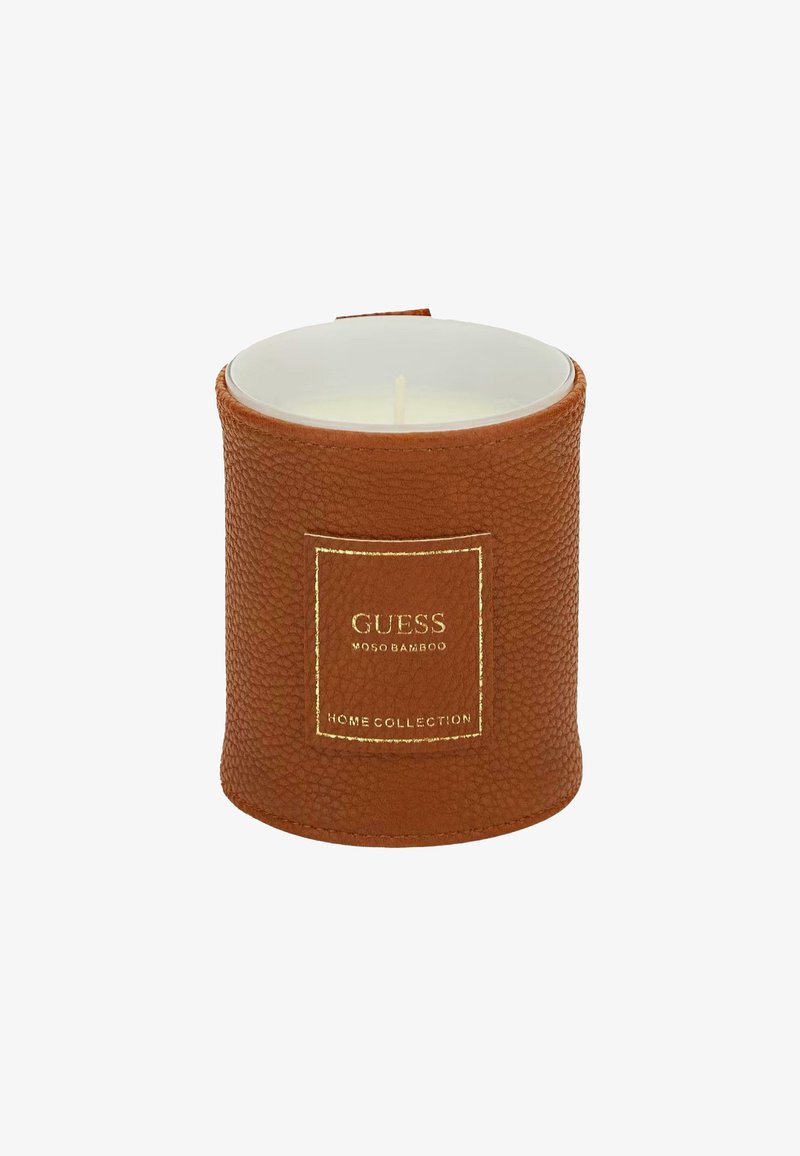 Portacandele texturato marrone con un contenitore interno bianco. Presenta un'etichetta con logo dorato. Forma rotonda con un top liscio e base piatta.