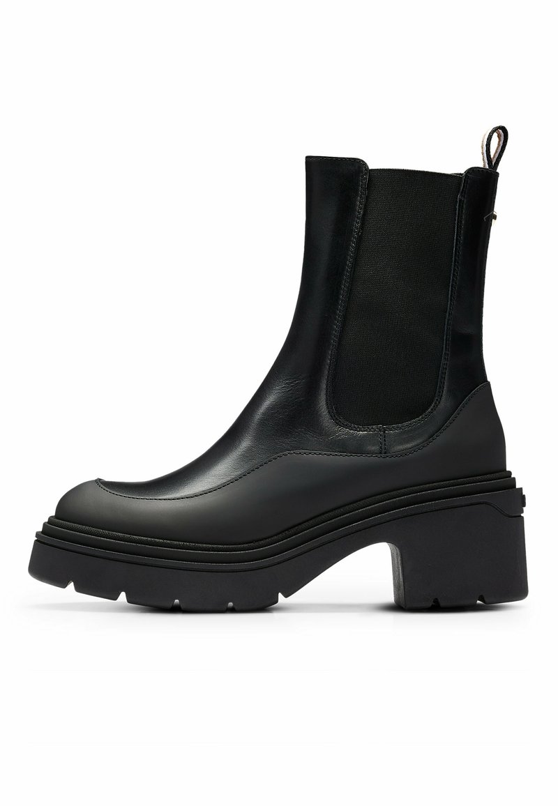 Bottine noire en cuir avec panneau latéral élastique, semelle épaisse à crampons et talon bloc, conçue pour un port durable et stylé.