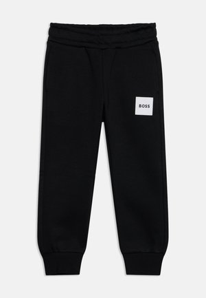 Schwarze Sweatpants mit elastischem Bund und Bündchen, Seitentaschen und einem kleinen weißen Patch mit der Aufschrift "BOSS" am linken Oberschenkel.