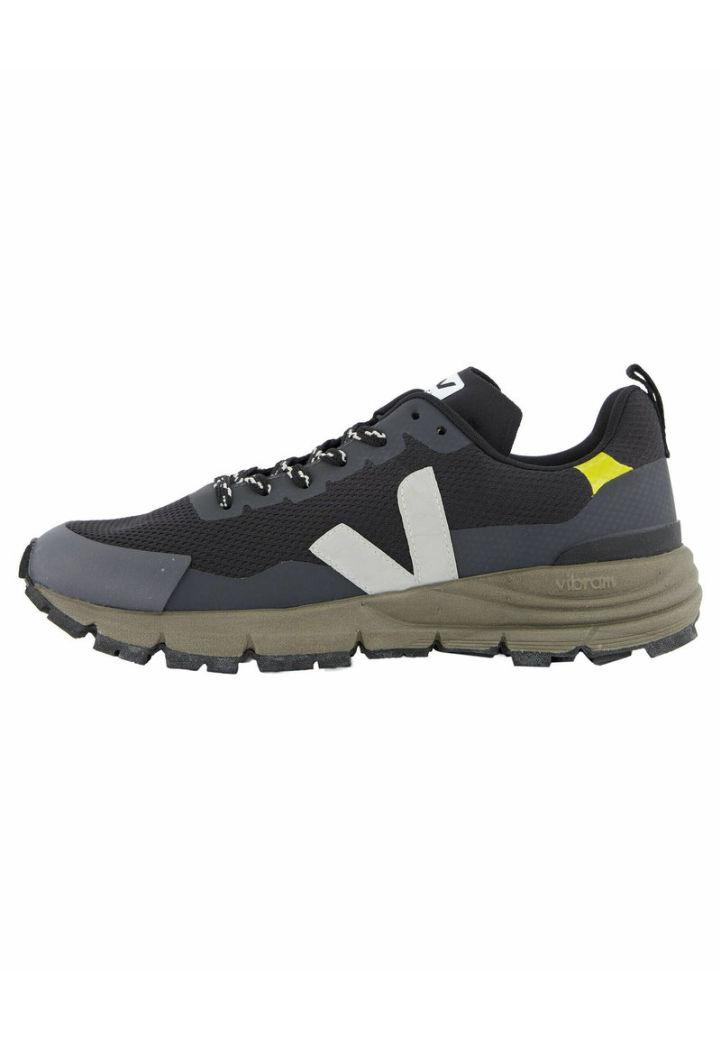 Scarpa sportiva nera e grigia con upper in mesh testurizzato, accenti bianchi, suola Vibram e lacci riflettenti. Presenta una suola spessa.